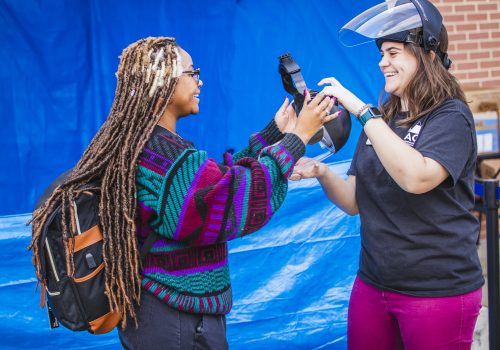A student putting on a paintball protective mask